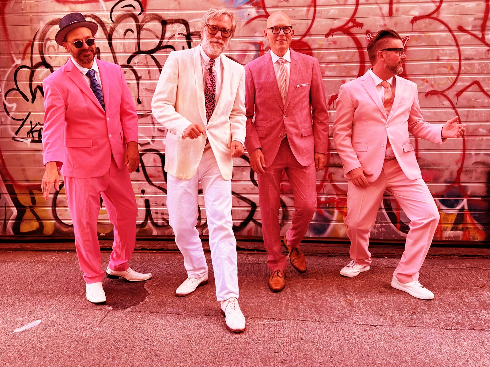 The Long Winters in pink and white suits in front of a graffiti wall